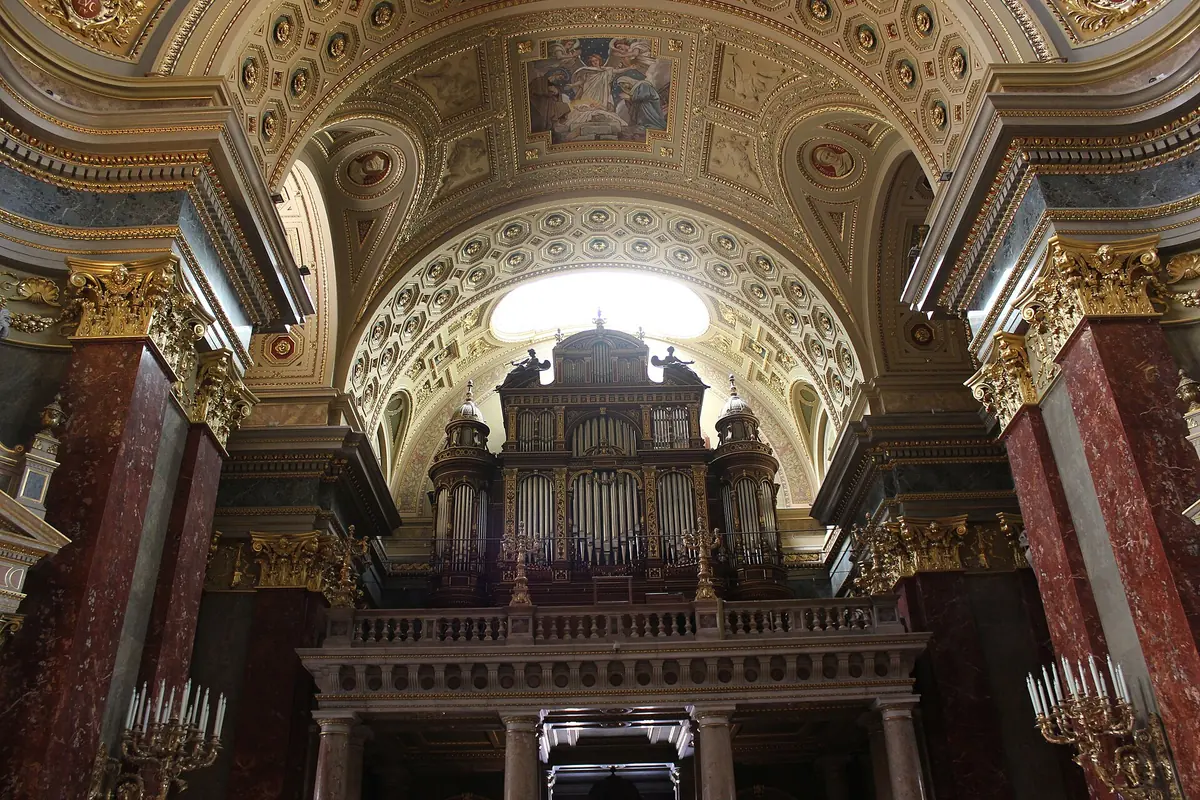 The organ gallery seen from the nave, with the organ case under a vault lit from above and chandeliers on either side.